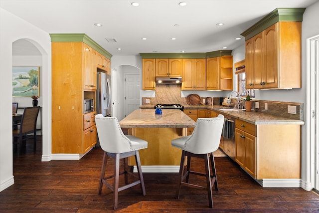 kitchen featuring a center island, backsplash, sink, dark hardwood / wood-style floors, and a breakfast bar area