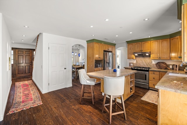 kitchen featuring dark hardwood / wood-style flooring, stainless steel appliances, a kitchen island, and tasteful backsplash