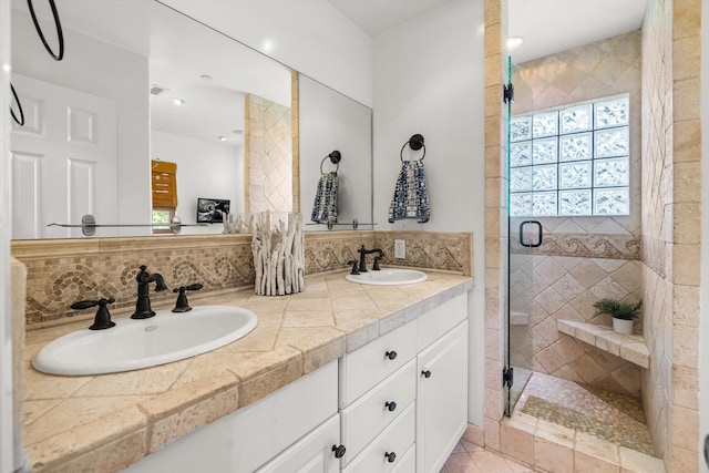 bathroom with vanity, walk in shower, and tasteful backsplash