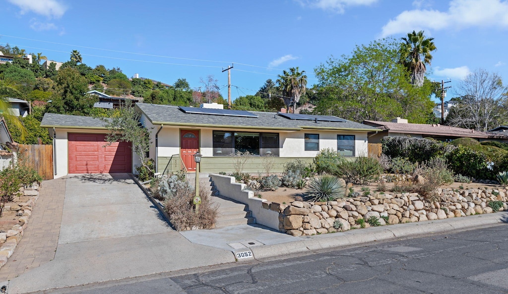 single story home with solar panels and a garage