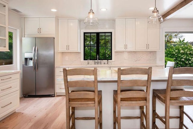 kitchen featuring sink, hanging light fixtures, stainless steel fridge with ice dispenser, beamed ceiling, and white cabinets