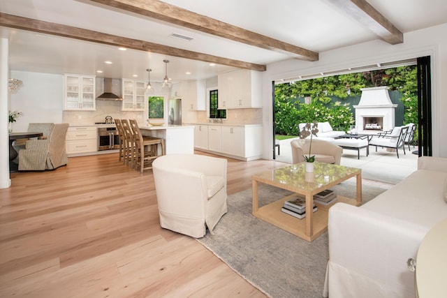 living room featuring beam ceiling, light wood-type flooring, and a wealth of natural light