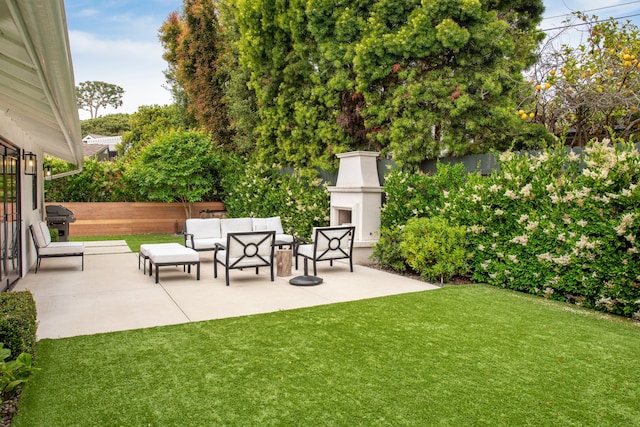 view of yard with an outdoor living space with a fireplace and a patio