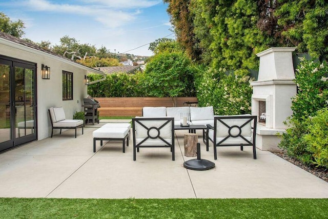 view of patio with an outdoor living space with a fireplace and grilling area