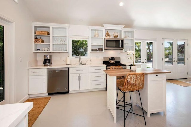 kitchen with a kitchen bar, appliances with stainless steel finishes, french doors, sink, and white cabinetry