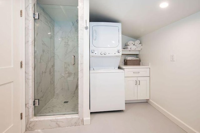 bathroom featuring lofted ceiling, vanity, stacked washer and dryer, and a shower with shower door