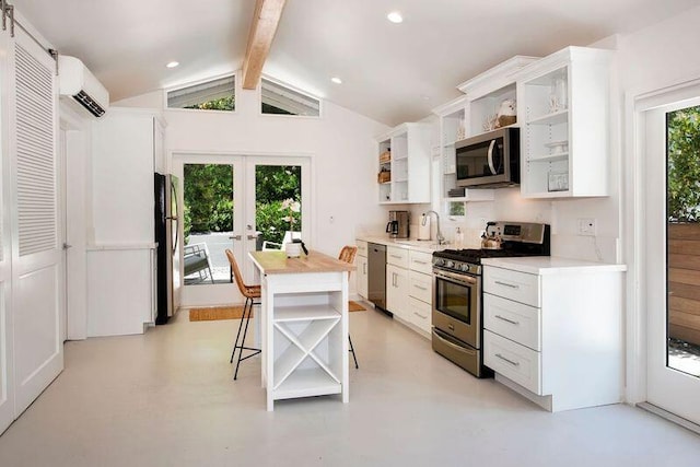 kitchen featuring a wall mounted AC, white cabinets, stainless steel appliances, and vaulted ceiling with beams