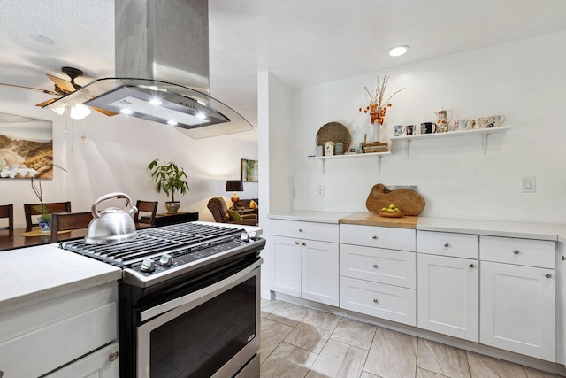 kitchen featuring white cabinetry, ceiling fan, stainless steel range with gas cooktop, a textured ceiling, and island range hood