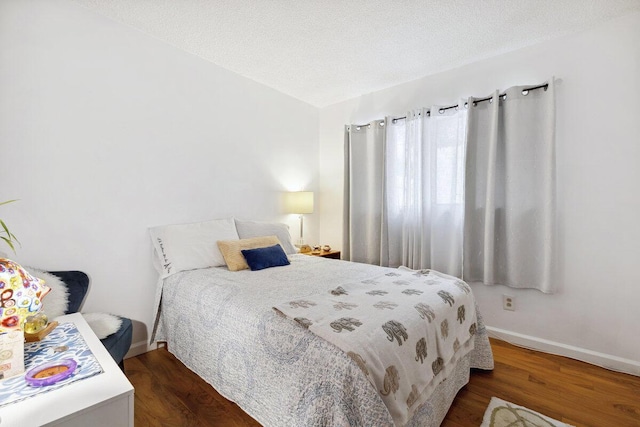 bedroom featuring dark hardwood / wood-style flooring and a textured ceiling