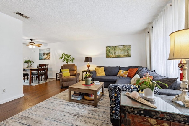 living room with ceiling fan, hardwood / wood-style floors, and a textured ceiling