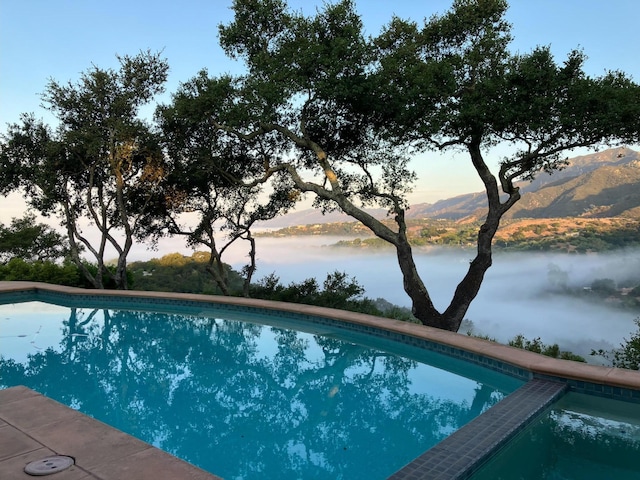 pool at dusk with a water and mountain view