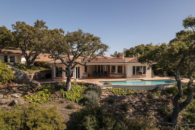 back of house with a swimming pool with hot tub and a patio area