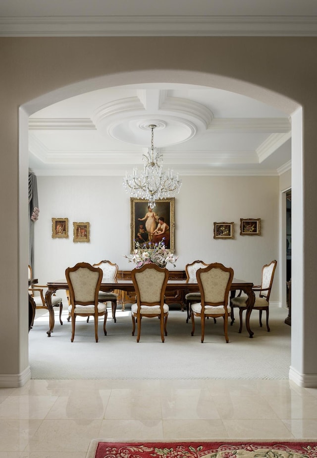 carpeted dining space featuring a notable chandelier, a tray ceiling, and ornamental molding