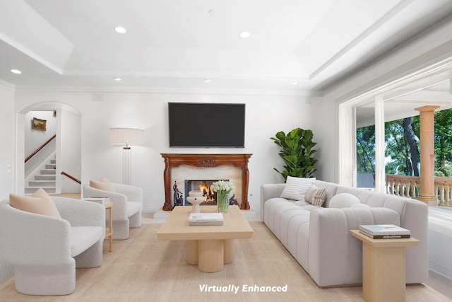 living room featuring a premium fireplace, a tray ceiling, and ornamental molding