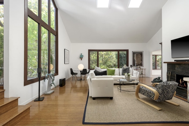 living room with plenty of natural light, high vaulted ceiling, and light wood-type flooring