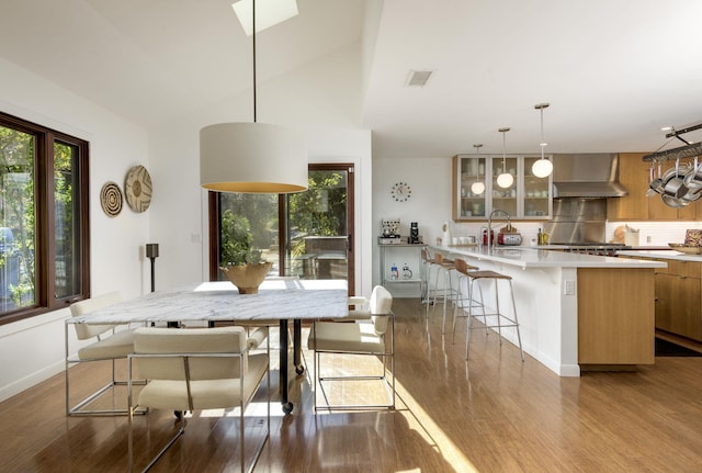 dining space featuring hardwood / wood-style floors, vaulted ceiling, and sink