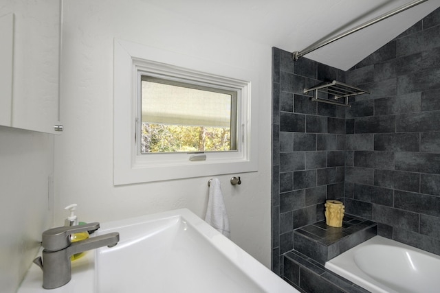 bathroom with vaulted ceiling and tiled shower / bath