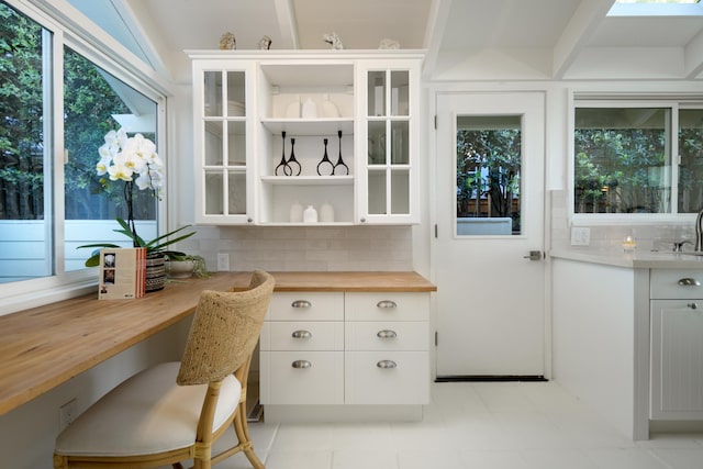 interior space featuring decorative backsplash, butcher block countertops, white cabinetry, and sink