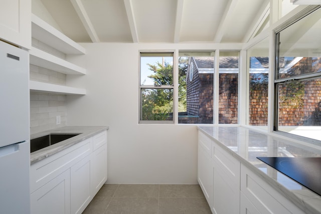 kitchen featuring white cabinets, white refrigerator, and light stone counters