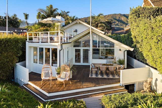 rear view of house featuring a deck with mountain view, french doors, and a balcony