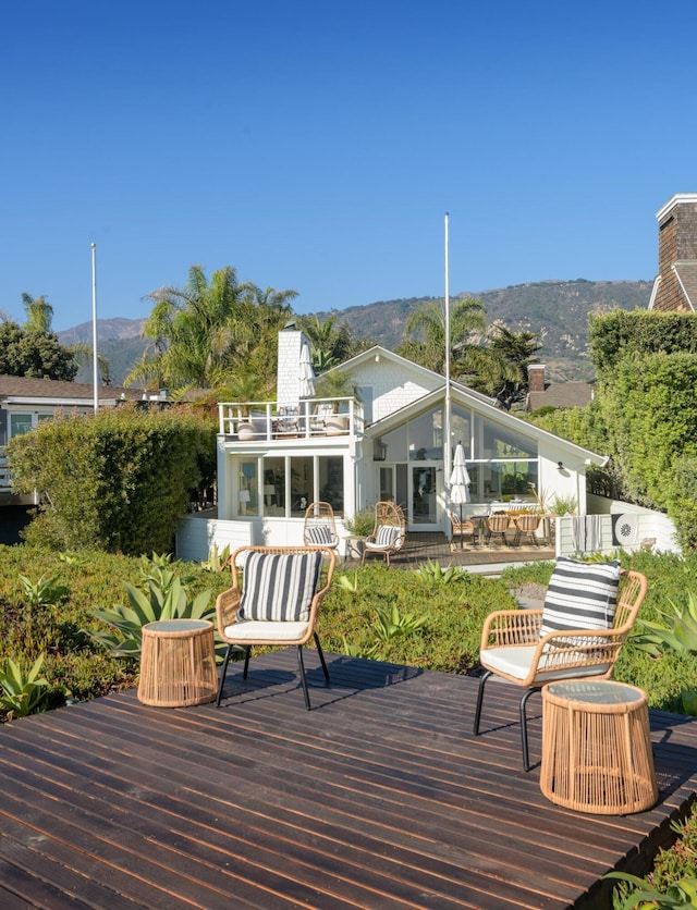 rear view of house with a balcony and a deck with mountain view