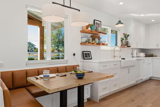 kitchen with pendant lighting, butcher block countertops, white cabinetry, and light hardwood / wood-style flooring