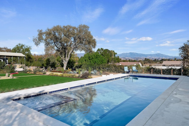 view of swimming pool featuring a lawn and a mountain view