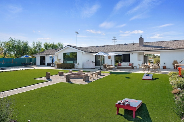 back of house with a yard, a patio, and an outdoor living space with a fire pit