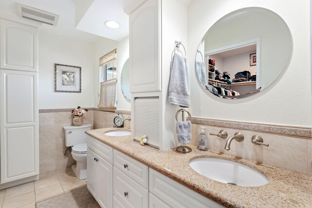 bathroom with tile patterned floors, vanity, toilet, and tile walls