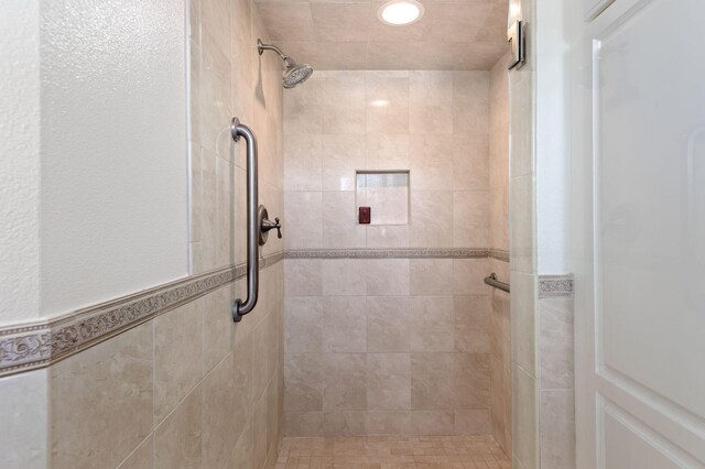 bathroom with a tile shower and tile walls