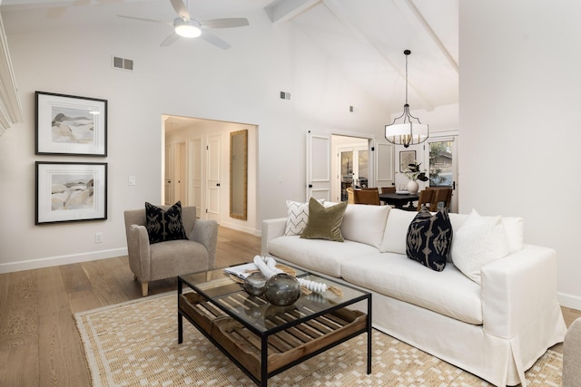 living room with beam ceiling, ceiling fan with notable chandelier, high vaulted ceiling, and light hardwood / wood-style flooring