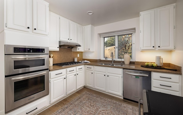 kitchen with decorative backsplash, white cabinetry, sink, and stainless steel appliances