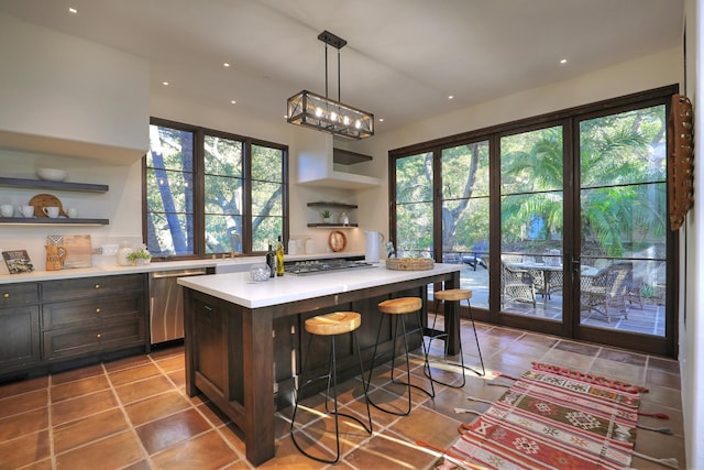 kitchen featuring dark brown cabinetry, a center island, stainless steel appliances, decorative light fixtures, and a breakfast bar