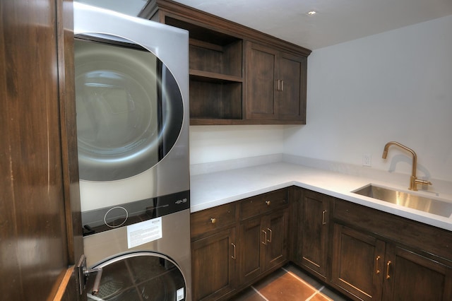 clothes washing area with cabinets, sink, light tile patterned flooring, and stacked washing maching and dryer