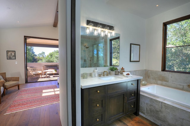 bathroom with shower with separate bathtub, vanity, vaulted ceiling, and hardwood / wood-style flooring