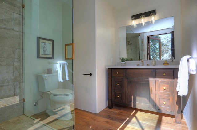 bathroom with wood-type flooring, vanity, toilet, and a shower with door