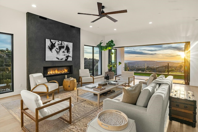 living room with a fireplace, light hardwood / wood-style floors, and ceiling fan