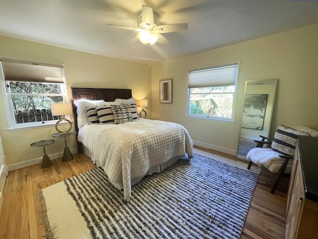 bedroom with ceiling fan, light wood-type flooring, and multiple windows