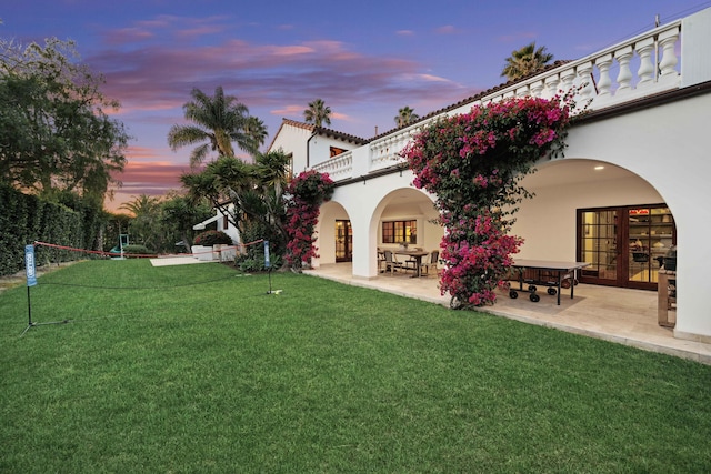 yard at dusk with a patio area and a balcony