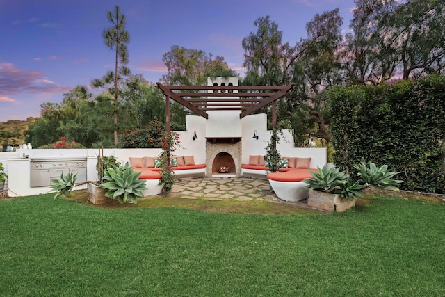 yard at dusk with an outdoor living space with a fireplace, an outdoor kitchen, and a patio