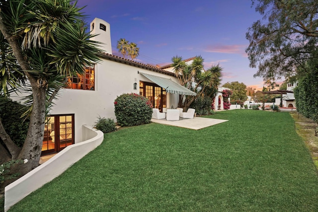 yard at dusk with french doors and a patio