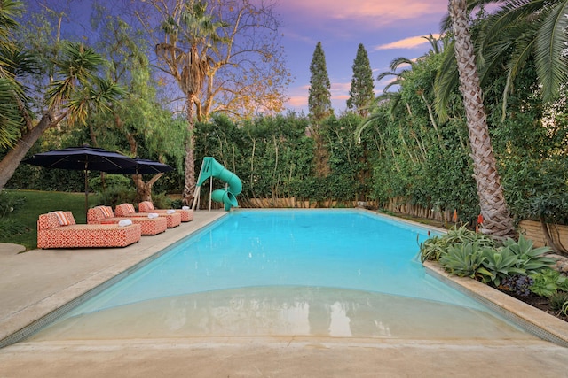 pool at dusk with a patio area