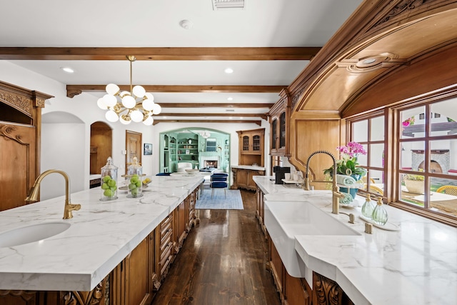 kitchen with sink, beamed ceiling, a notable chandelier, pendant lighting, and a kitchen island