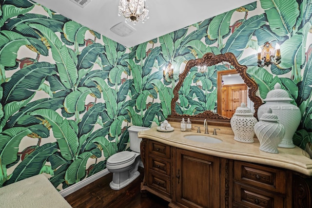 bathroom with hardwood / wood-style floors, vanity, toilet, and a notable chandelier