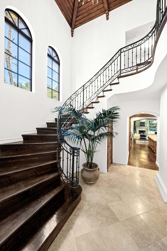 staircase featuring beamed ceiling, wooden ceiling, and a high ceiling