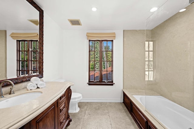 bathroom with a washtub, a healthy amount of sunlight, toilet, and vanity