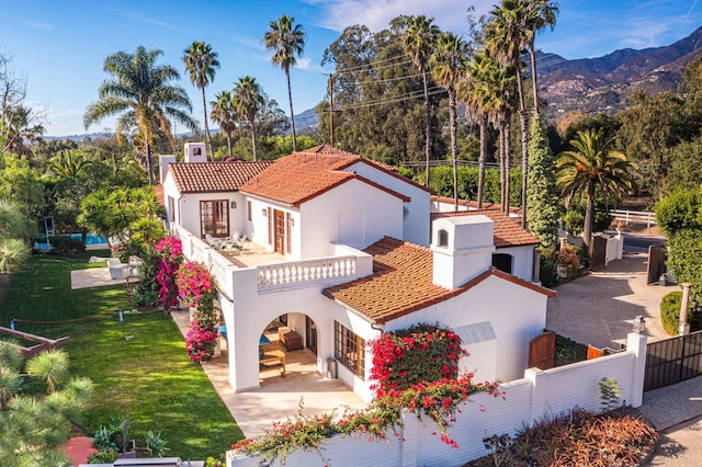 back of property with a yard, a mountain view, and a balcony