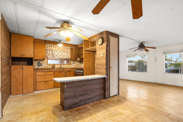 kitchen with tasteful backsplash, kitchen peninsula, sink, and stainless steel stove