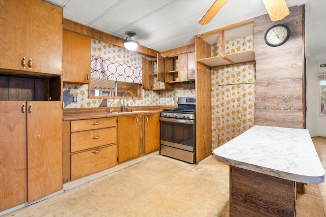 kitchen with wood walls, a healthy amount of sunlight, stainless steel range with gas cooktop, and sink