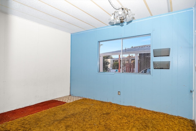 carpeted spare room featuring a chandelier